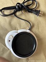 Top view of white MerchSource beverage warmer with black heating plate, attached cord and plug