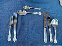 Flatware pieces laid out showing pattern on forks, spoons and knives