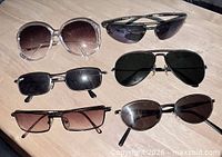 Six pairs of sunglasses laid out on table