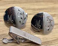 Front view of cufflinks and tie clip showing engravings and monogram