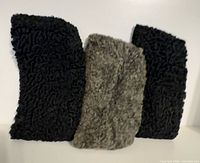 Front view of three Persian lamb fur hats (two black, one gray) standing upright