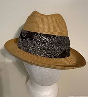 Front angled view of straw fedora showing crown, brim, paisley band