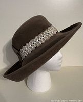 Side view of brown wide brim fedora showing metallic braid band and brim shape