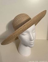 Front angled view of woven straw sun hat on mannequin head