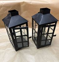 Two black metal lanterns front view with doors ajar