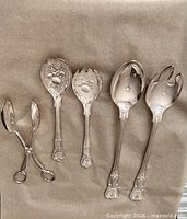 Group shot of all five silver-plated serving pieces on paper background