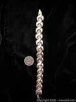 Full view of bracelet beside coin for scale