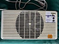 Top view of booster fan showing grille, fan opening, attached power cord