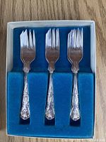 Three silver-plated dessert forks in blue flocked insert
