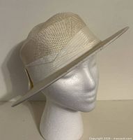 Front angled view of ivory straw hat on display form