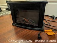Front view of electric fireplace heater showing faux logs and glass front