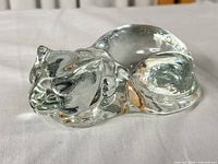 Full side view of clear glass cat figurine on white cloth