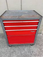 Front view showing Craftsman badge, three shallow drawers, large bottom door, casters