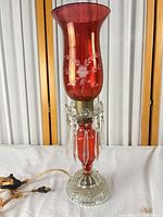 Full view of cranberry glass hurricane lamp with prisms and cord