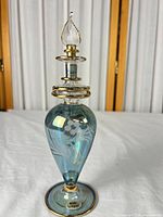 Full view of blue-green iridescent glass perfume bottle with stopper