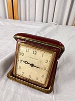 Clock front, dial visible in open red leatherette case