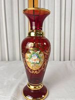 Full view of ruby red vase with enamel floral medallion and gold scrollwork