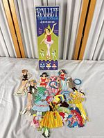 Entire lot: box, four paper dolls with stands, wardrobe pieces spread out
