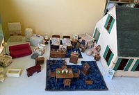 Assorted miniature furniture arranged in front of dollhouse, showing quantity and types