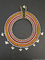Full view of circular multicolour beaded collar necklace with triangular dangles