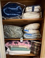 Shelf with multiple folded comforters and blankets