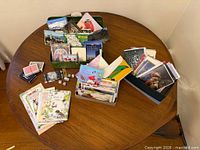 Mixed greeting cards, postcards, playing cards, dice and open green tackle box displayed on table