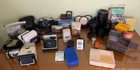Overall view of all cameras, lenses, slide viewers, meter, lantern and accessories spread on table