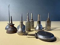 Ten small metal oil cans displayed on surface