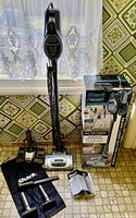 Vacuum assembled with wand and nozzle standing beside box, accessories and bag displayed