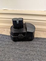 Side view of black 18V battery pack showing latch mechanism and housing wear