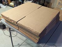 Stack of flattened corrugated boxes on table