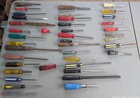 Full layout of approximately forty screwdrivers, files, nut drivers and awl on tabletop