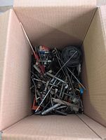 Top view of cardboard box showing mixed metal tool parts and hardware