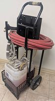Front view of cart with hose, spray gun, jug and wheels