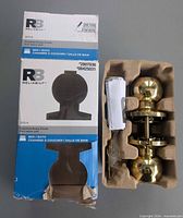 Box front and contents showing Reliabilt Bola polished brass knob set