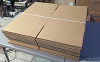 Top view of strapped stack of flat cardboard box blanks on table