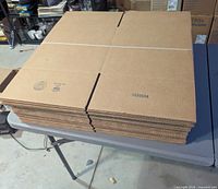 Stack of flat-packed corrugated boxes on table, banded together