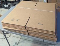 Stack of flat collapsed Uline boxes on table showing top surface and printed part number