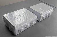 Two factory-wrapped white junction boxes side view showing knockouts