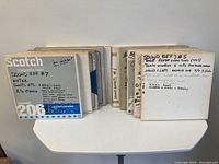 Front view of stacked tape boxes; Scotch branding and handwritten labels visible