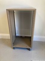 Front view of empty beige metal rack on casters showing vertical rails