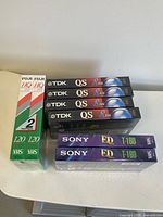 Stacked view of all eight sealed VHS tapes showing brands and models