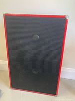 Front of red-trimmed cabinet with black grille
