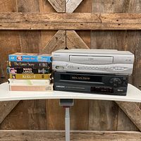 Front view of two VCRs stacked with six VHS tapes beside them