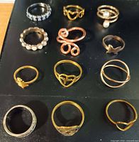 All 12 rings laid out in four rows on black surface