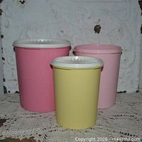 Three pastel Tupperware canisters grouped to show relative sizes and colors