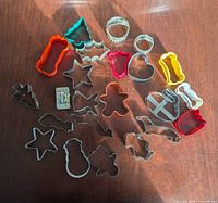Overhead view of twenty-three assorted cookie cutters spread on wooden surface