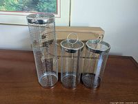 three sizes of stainless steel mesh rolling grill baskets standing side by side