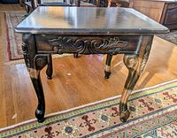 Single carved dark wood end table showing apron detail and legs
