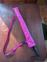 Umbrella inside pink sleeve with adjustable strap